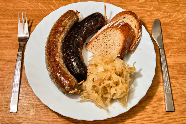 gustosa jitrnice tradizionale ceca, salsiccia e jelita, salsicce di sangue, con cavolo triturato e pane su piatto bianco su tavolo di legno con vista dall'alto della forchetta e del coltello - sausagemeat foto e immagini stock