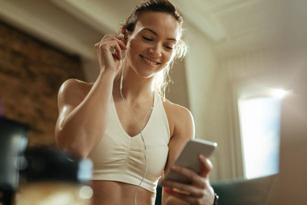 Below view of athletic woman using smart phone at home.