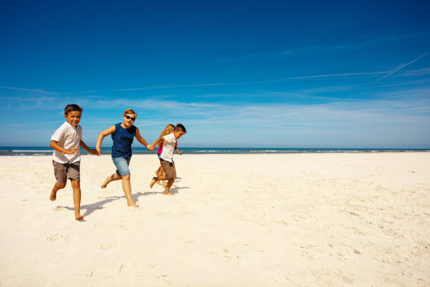 istock Happy kids play on the sand beach holding hands 1210123522