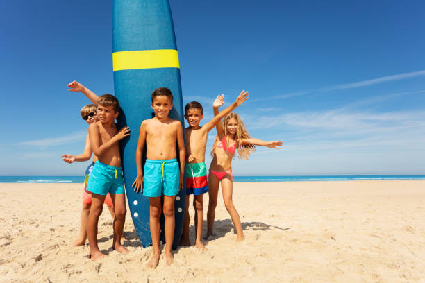 istock Boy with friends stand by surfboard on the beach 1210123590