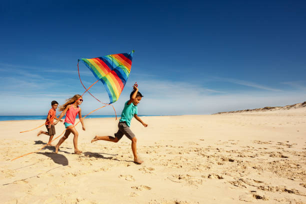 istock Many children run away with color kite on a beach 1210123686