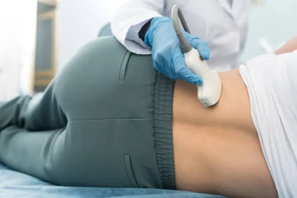 partial view of professional doctor examining kidney of patient with ultrasound scan in clinic