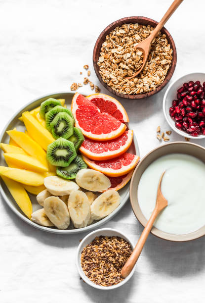 istock Breakfast set table - fresh tropical fruits, greek yogurt, granola on a light background, top view. Delicious healthy diet food concept. Flat lay 1210126401