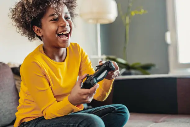 Young African American little girl at home with playing video games