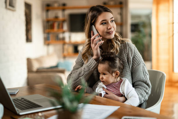 Young mother with small daughter talking on the phone at home. Smiling mother holding small daughter in her lap while talking on the phone at home. house phone stock pictures, royalty-free photos & images
