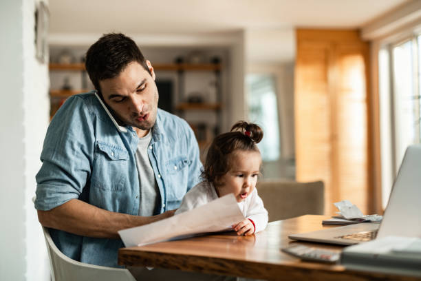 istock Young father with daughter talking on the phone while working at home. 1210127082