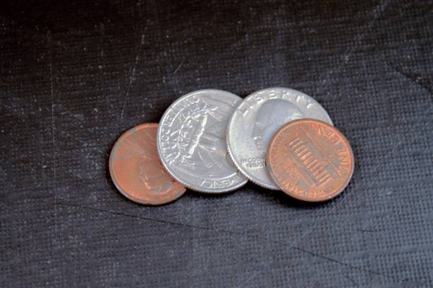 istock Two one-cent coins and two quarter dollar coins lying on a black background. in grunge style 1210127338