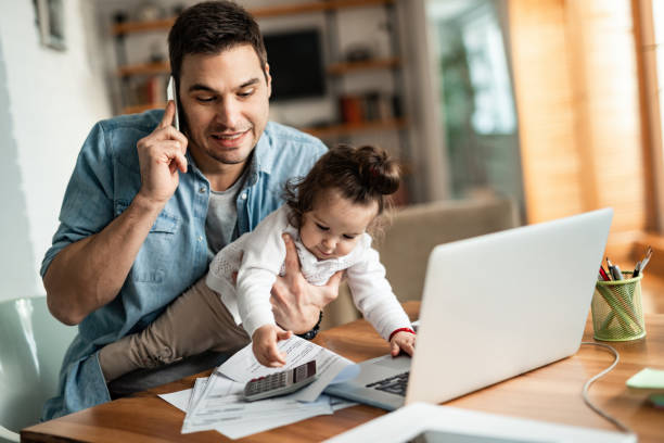 Please, don't mess up my reports! Young working father talking on the phone while babysitting his playful daughter at home. working hard stock pictures, royalty-free photos & images