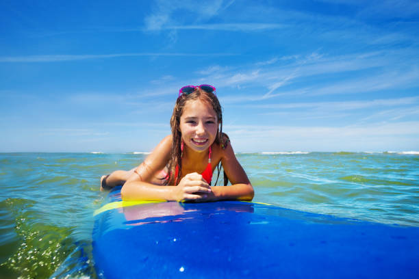 istock Happy surfer girl lay on surfboard wait for wave 1210129086