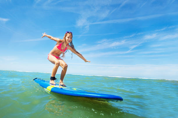 istock Happy beautiful girl learn to surf on surfboard 1210129094