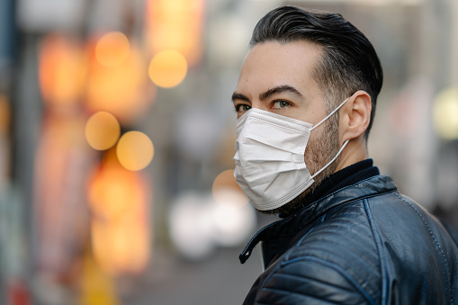 A man is covering covering his mouth and nose with a pollution mask to protect himself from coronavirus, cold virus, flu virus, pollution.