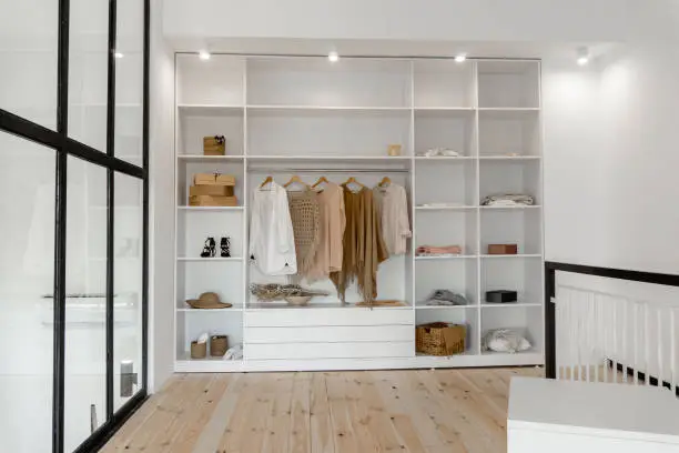 Vew on open space minimalistic scandinavian white wood walk in closet and wardrobe in neutral beige colors