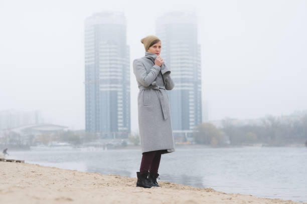 istock Young woman walking away alone wearing a grey overcoat 1210132873