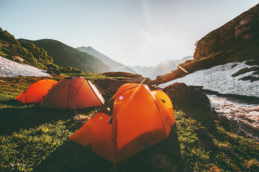 Camping tents in mountains morning sun landscape Travel Lifestyle concept adventure summer vacations outdoor hiking gear equipment