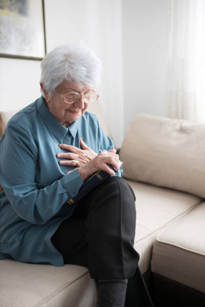 istock Senior white-haired woman having heart attack while reading a book at home 1210134649