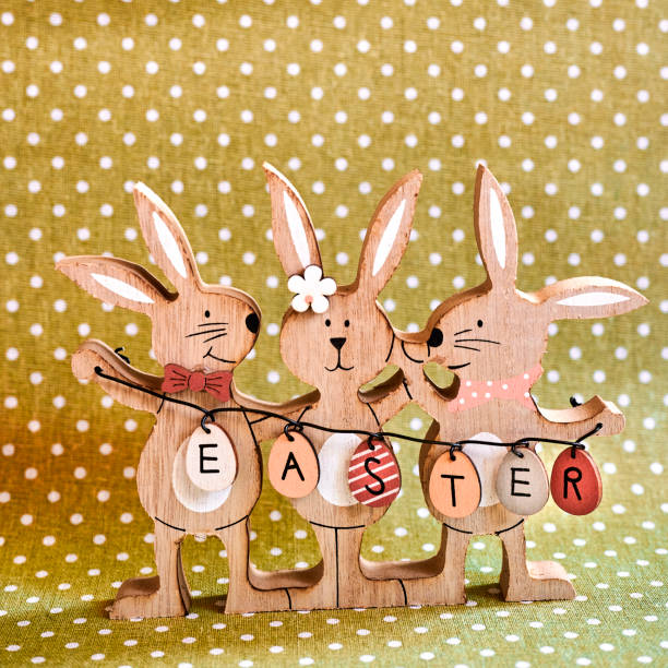 Three wooden Easter bunnies with painted decoration and the text Easter written on eggs.