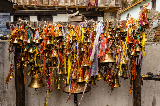 Muktinath, Nepal - April 2015: Bronze temple bells with prayers written on colorful ribbons inside the ancient Hindu temple at Muktinath in Mustang, Nepal.