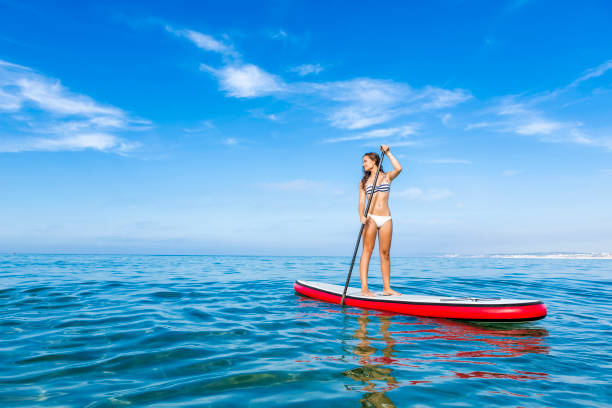 vrouw die peddel praktizert - paddle surfing stockfoto's en -beelden