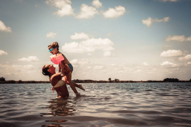 istock Playful mother and son having fun in water during summer day. 1210136101