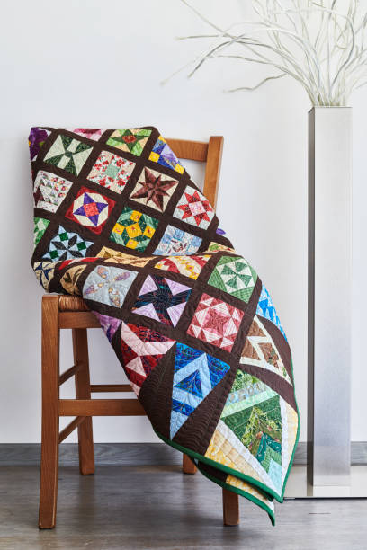istock Folded quilt on a chair and floor lamp against a neutral wall 1210136418