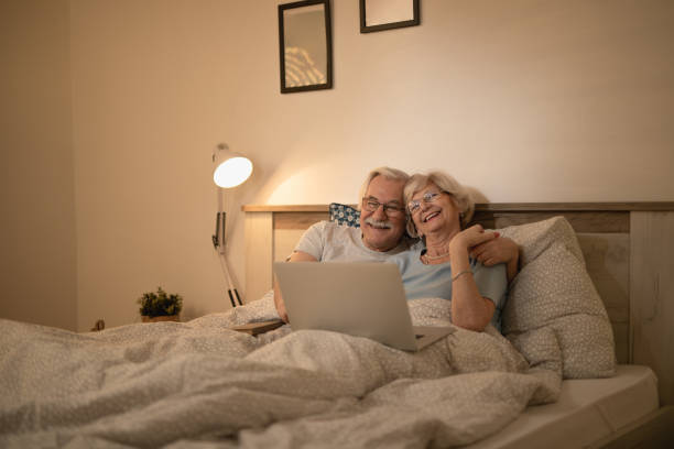 istock Happy mature couple having fun while using laptop in bedroom. 1210139545