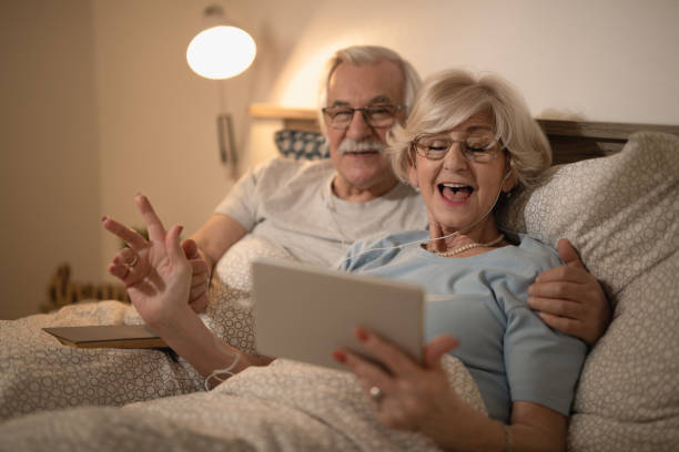 istock Cheerful mature woman having fun while using touchpad with her husband in bedroom. 1210140357