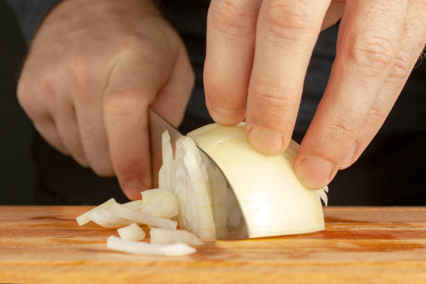 istock Men 's hands are cut with a cook 's knife bulb onions on a cutting board 1210140391