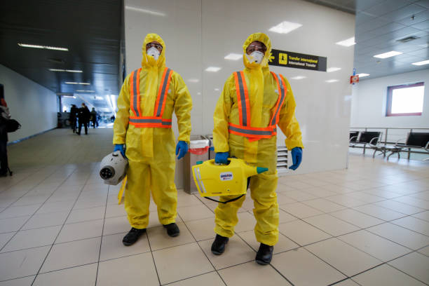 People wearing protective suits spray disinfectant chemicals on the Henri Coanda International Airport to prevent the spreading of the coronavirus Otopeni, Romania - February 25, 2020: People wearing protective suits spray disinfectant chemicals on the Henri Coanda International Airport to prevent the spreading of the coronavirus. bucharest people stock pictures, royalty-free photos & images