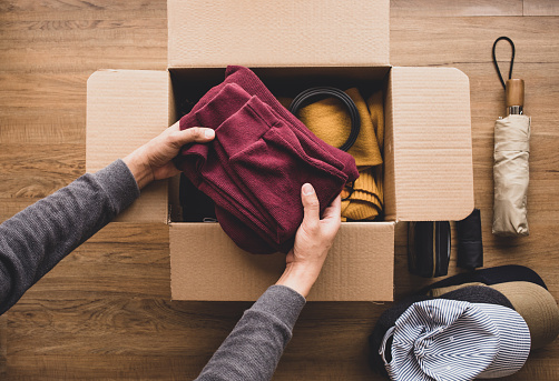 Cleaning home and donation concepts with young person putting accessories clothing in brown box.giving and sharing with human.second hand or recycle product ideas