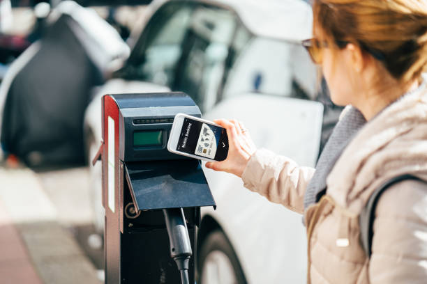 frau zahlt kontaktlos für das laden eines elektroautos - benzin sparen stock-fotos und bilder