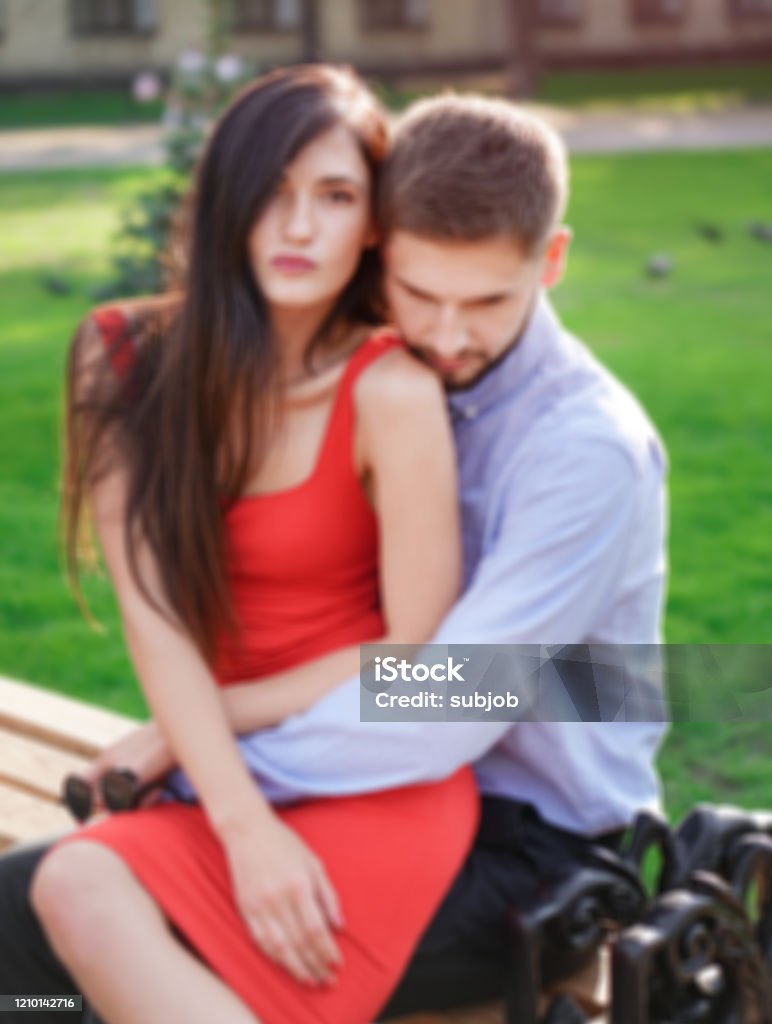 Beautiful Couple Of Man And Woman Sitting On A Bench In A Park ...