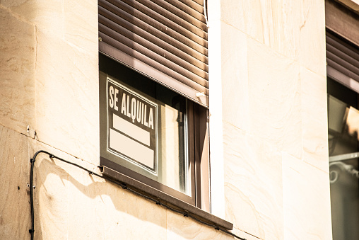 A 'Se alquila' (For rent) sign on an apartment window in Spain
