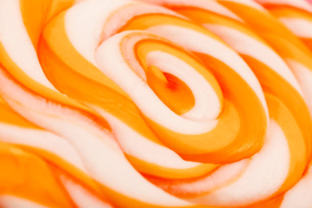 Orange round Lollipop on pink background. Minimal concept with copy space. Confectionery, sweets. Close-up, macro, texture