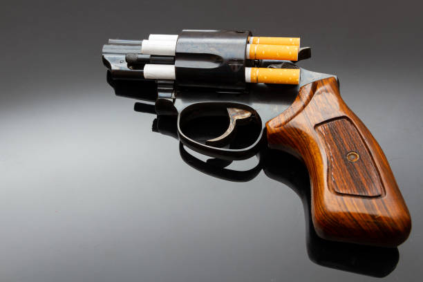 istock Dangerous short revolver with cigarettes as bullets on shiny surface 1210144941