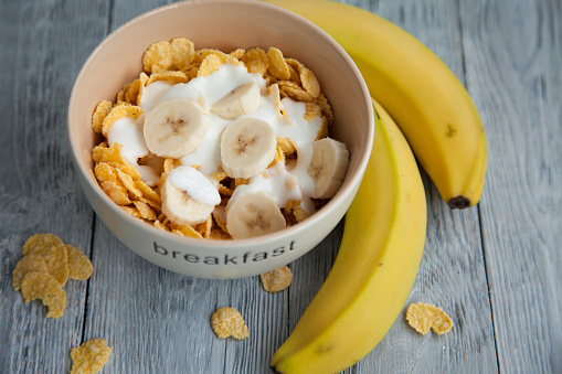 Healthy breakfast with glass of milk,bananas and corn flakes. Top view, the wooden background