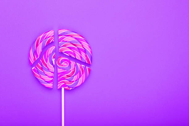 Pink Lollipop split into pieces on a pink background, top view, close-up. The concept of the holiday sweet candy.