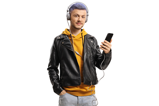 Trendy young guy listening to music on headphones connected to a smartphone isolated on white background