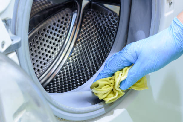 Cleaning the bathroom. Woman is cleaning washer (washing machine) with a rag in rubber gloves. stock photo