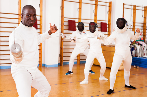 Sporty african american man fencer practicing effective fencing techniques in a training room