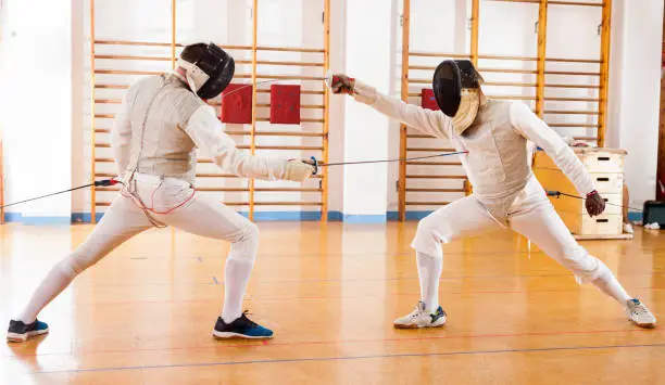 Group of fencers at fencing workout, exercising the techniques in a battle