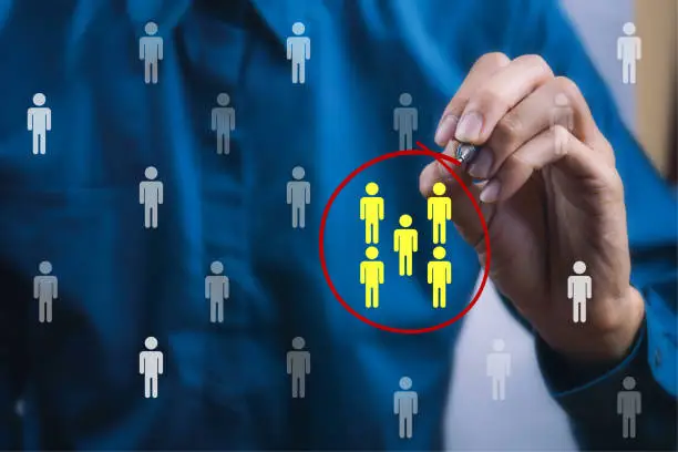 Photo of Teamwork or focus niche marketing concept. A businessman write a red line circle around yellow businessman icon.