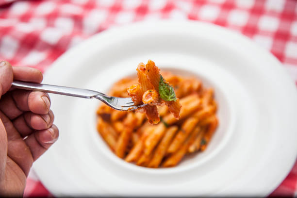 Italian Penne Arrabiatta on the top Parmesan cheese on Table with fork