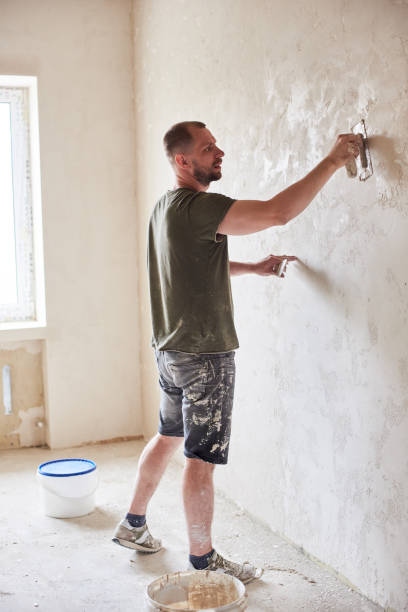 master is applying white putty on wall and smearing by special knife in room of renovating apartment at daytime - plasterer plaster wall dirty imagens e fotografias de stock