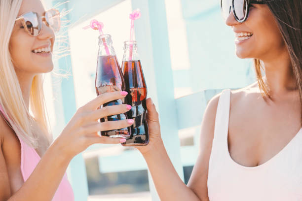 istock Happy girls drinking lemonade at sunny beach 1210161561