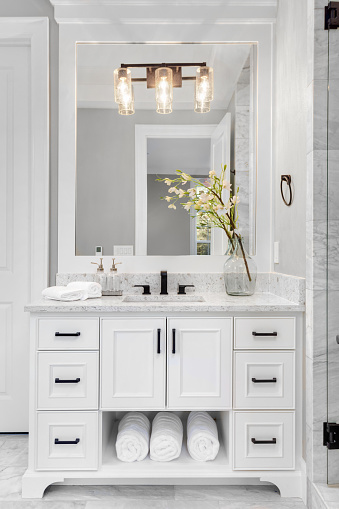 Hermoso interior de baño en nueva casa de lujo con tocador, espejo y gabinetes photo