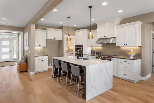 Photo of beautiful kitchen in new home with island, pendant lights, and hardwood floors.