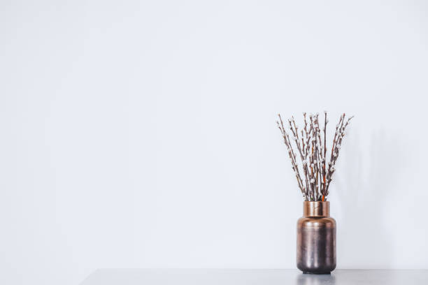 istock Twigs with buds in a vase against the white wall. 1210163788