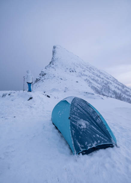 istock Man climber with tent camping on snow mountain peak in gloomy 1210163926