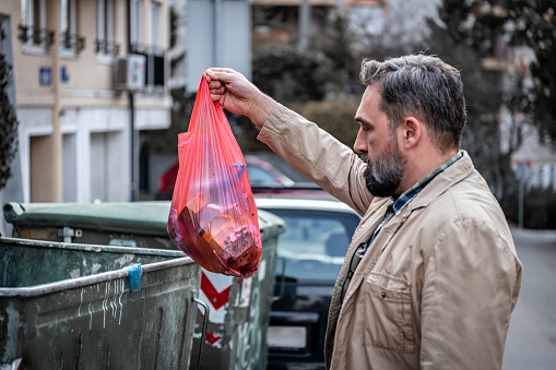Man hand holding garbage in bag for cleaning in to trash. Bearded Mid Adult Man Throwing Trash.