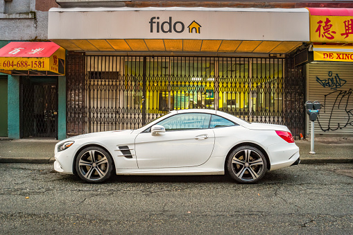 A white colored Mercedes 450 SL Roadster is parked on the street in Vancouver Canada.